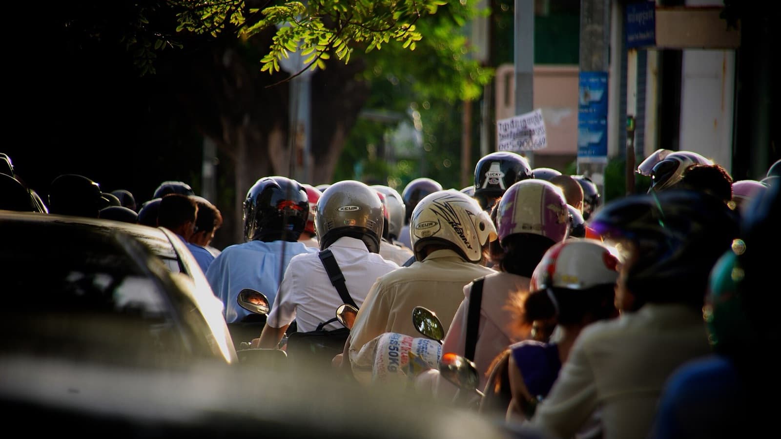 Dense rush-hour traffic of motorbike riders in helmets on a Phnom Penh street